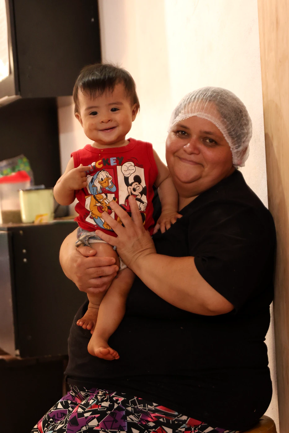 Bebê sorrindo no colo de uma cuidadora durante uma ação no Paraguai