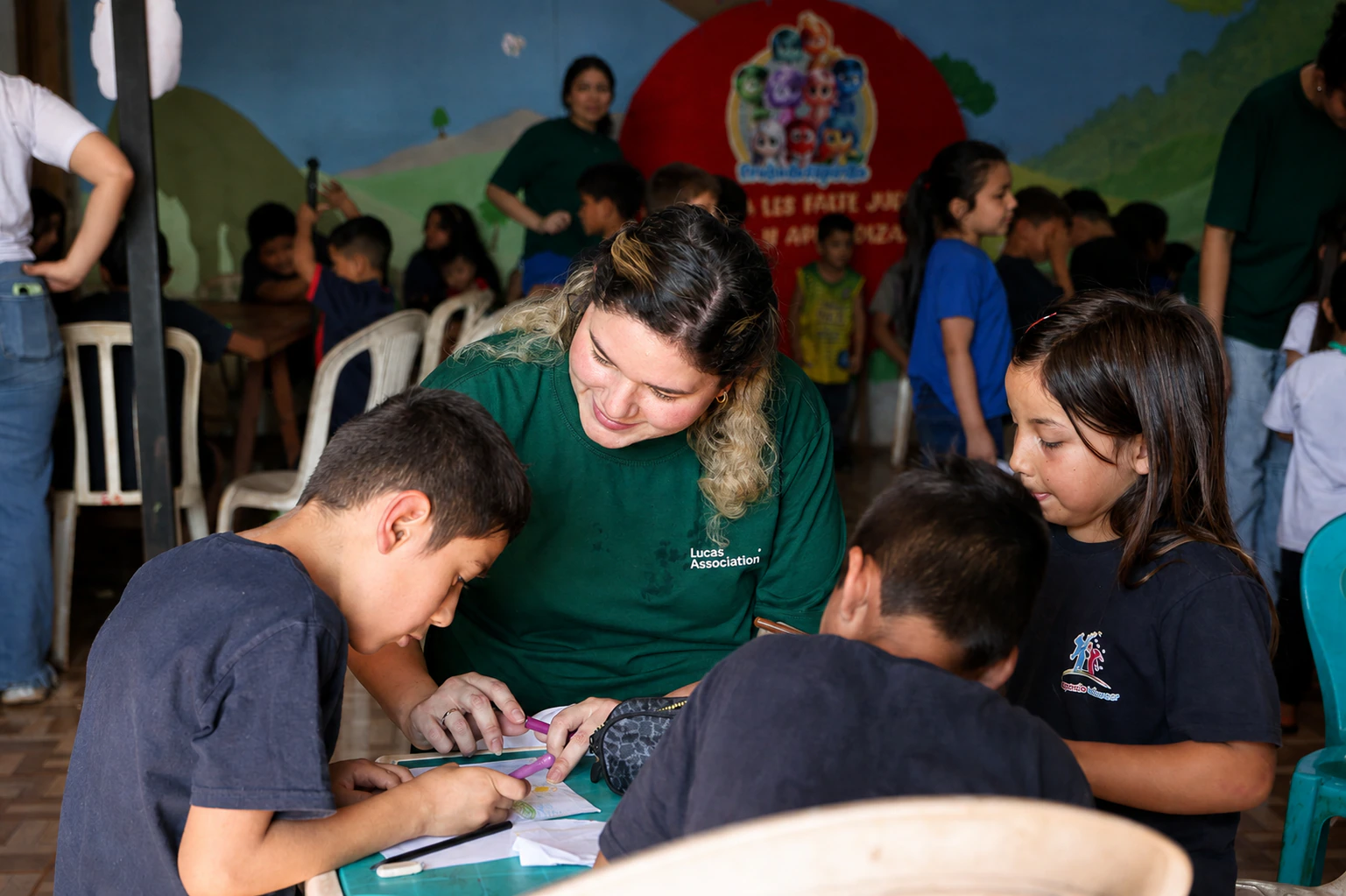Voluntária acompanha crianças durante atividade educativa
